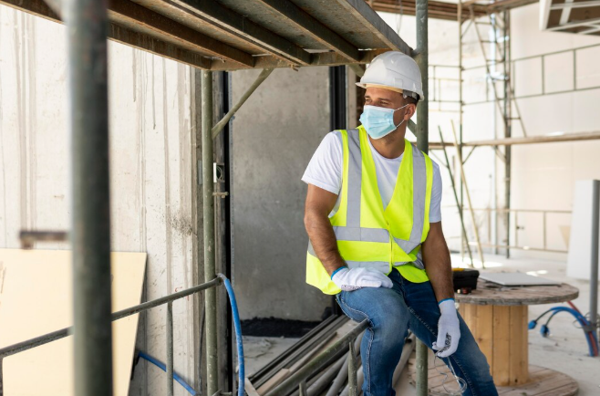 Obrero en construcción con casco y chaleco de seguridad.