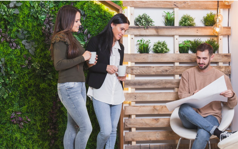 Personas revisando planos en espacio moderno con diseño biofílico y decoración natural.